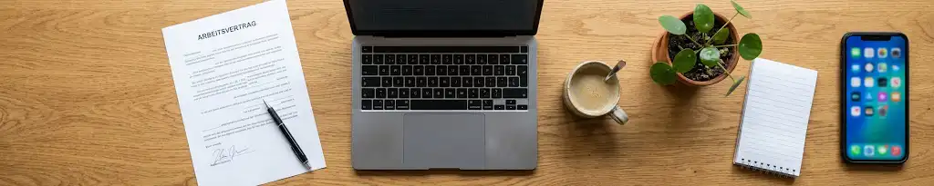 Arbeitsvertrag für einen Minijob im Homeoffice neben Laptop und Smartphone